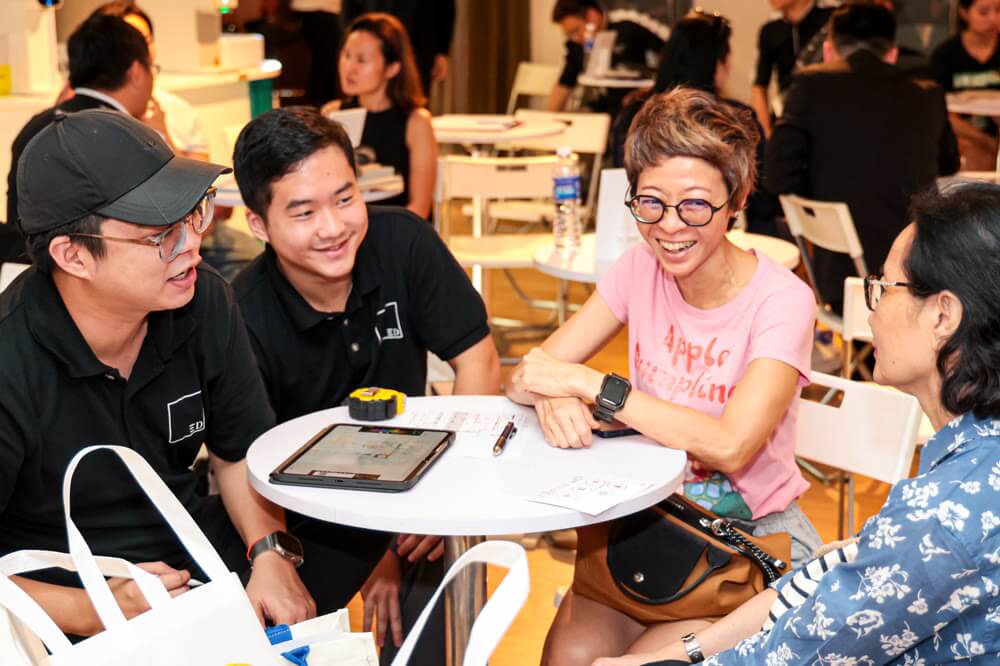 Homeowners laughing with a designer at a consult table